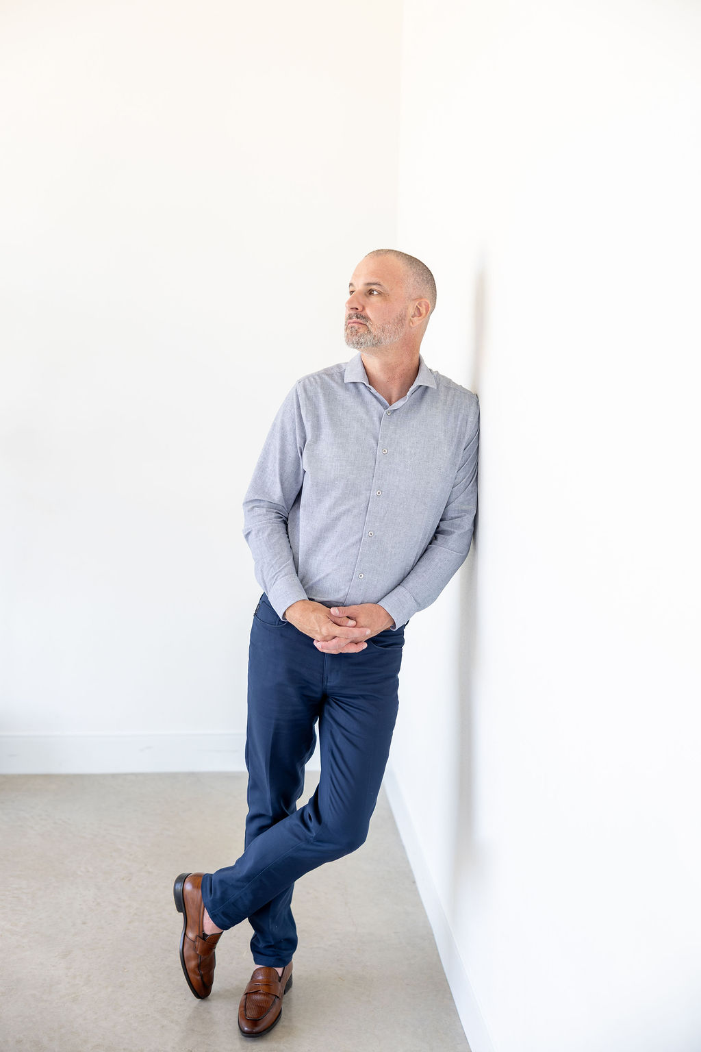 James Scott Henson standing in a light gray shirt and navy trousers, listening thoughtfully